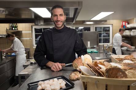 Gregor Smolinsky mit Coquilles St-Jacques in der Küche.