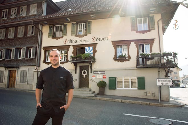 Mann in schwarzer Kochuniform vor historischem Gasthaus