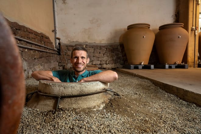 Vincent Gross hebt Wein aus vergrabener Amphore schaut aus einer Tonamphore