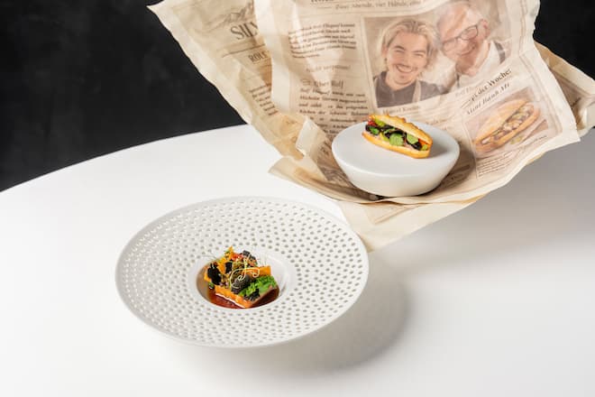 Four-Hands-Dinner mit Marcel Koolen und Rolf Fliegauf im Restaurant 7132 Silver in Vals. Gericht von Marcel Koolen, Mini Bahn Mi: Dampfbroetchen mit Sauerteig, Fuellung Schweinebauch, mariniert mit Fischsauce, Knoblauch, Chili, frische Kraeuter dazu Schweine-Kinn mit Kohlrabi-Kimchi, Liebstoeckel-Creme, Flower Sprouts, Trueffel-Kohl-Sauce. Fotografiert am 20. Maerz 2026 fuer GaultMillau. Bild Yanik Buerkli