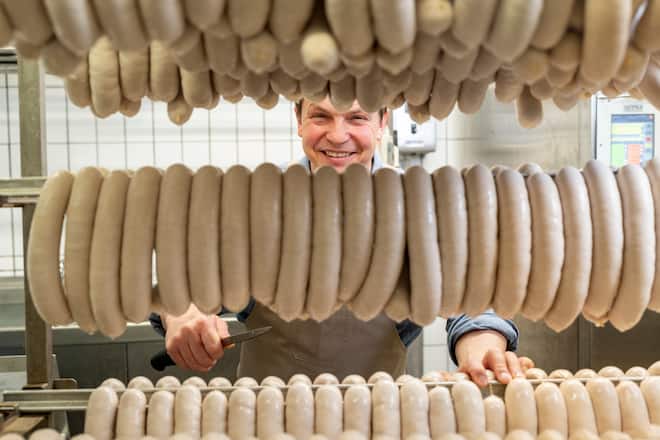 Bechinger Bratwuerste, St. Gallen-St Georgen, Jörg Bechinger schneidet die Olmabratwurstschlange mit dem Messer in einzelne Würste