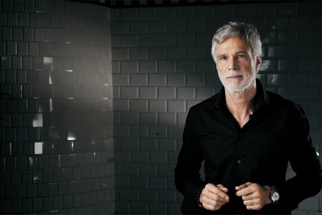 Mann in schwarzem Hemd vor schwarzem Hintergrung