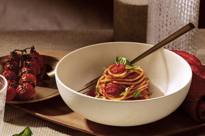 Weisse Schüssel mit Spaghetti an Tomatensauce in rustikalem Ambiente