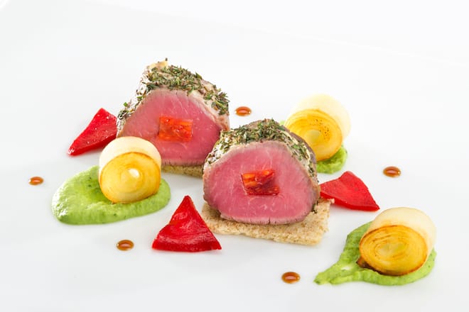 Carré d’agneau piqué au chorizo et pané au thym, purée de pois à la menthe, piquillos et pommes confites