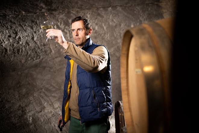 Le vigneron Steve Bettschen, pose dans sa cave avec un verre de vin blanc à la main, le mardi 15 février 2022 à La Sarraz. (© Gabriel Monnet/ Gault & Millau)