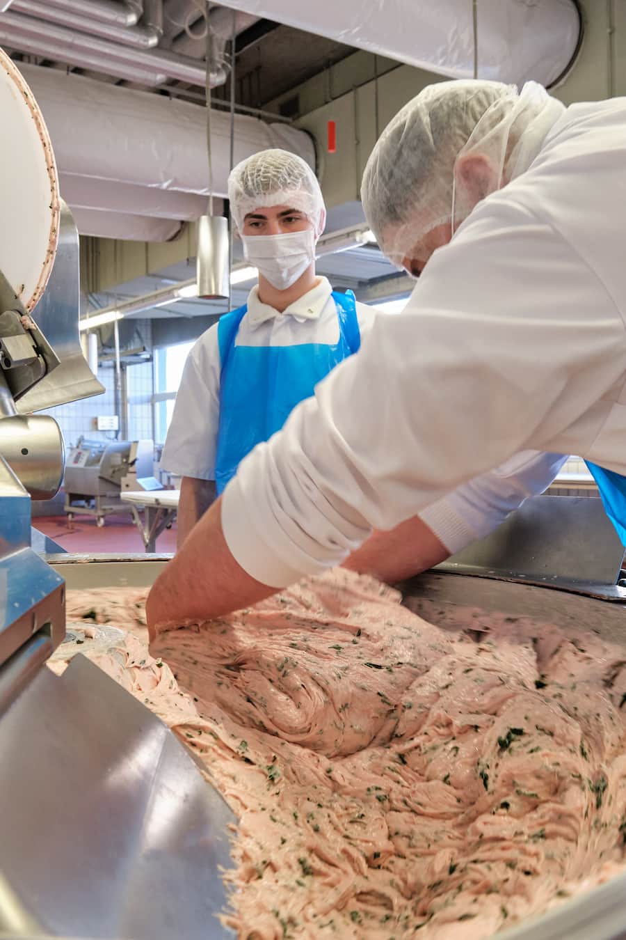 Antonio und Betim geben Spinat in die Schüssel, Manuel vermengt diesen.