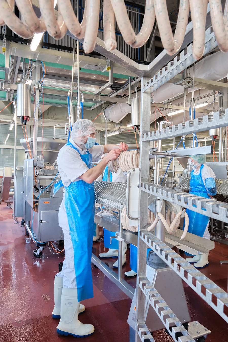 Lukas hängt die Würste am Edelstahl-Stecken auf und verteilt diese gleichmässig.