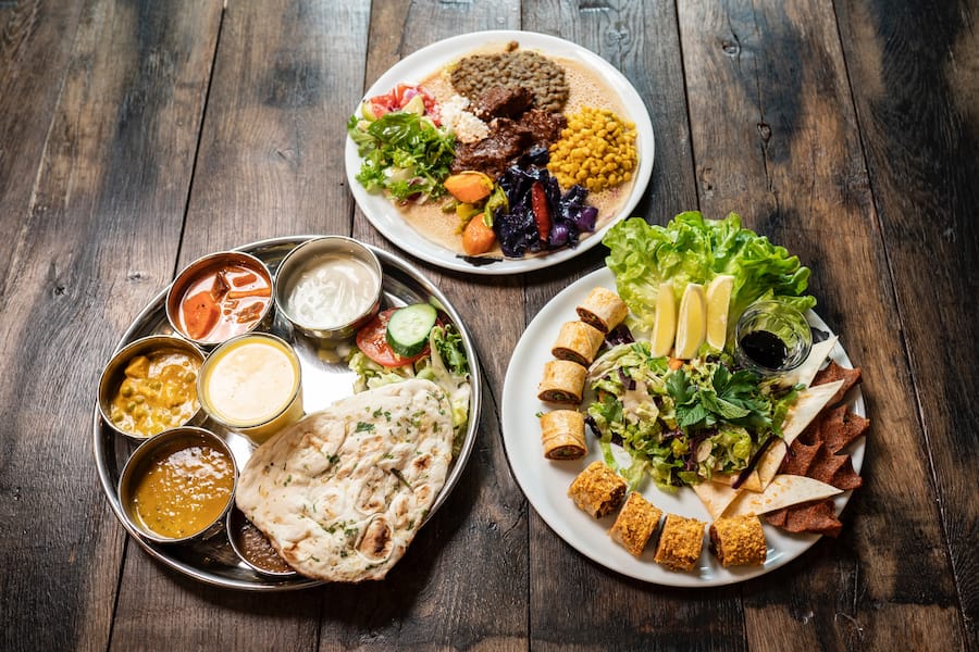 Simone Jones Chef-Foodscout bei Betty Bossi, in der Markthalle in Basel, v.l.n.r.: indische Currys, Reis und Naanbrot; äthiopisches KeyWot mit Rindsragout; türkische, vegane Koefte aus Bulgur
