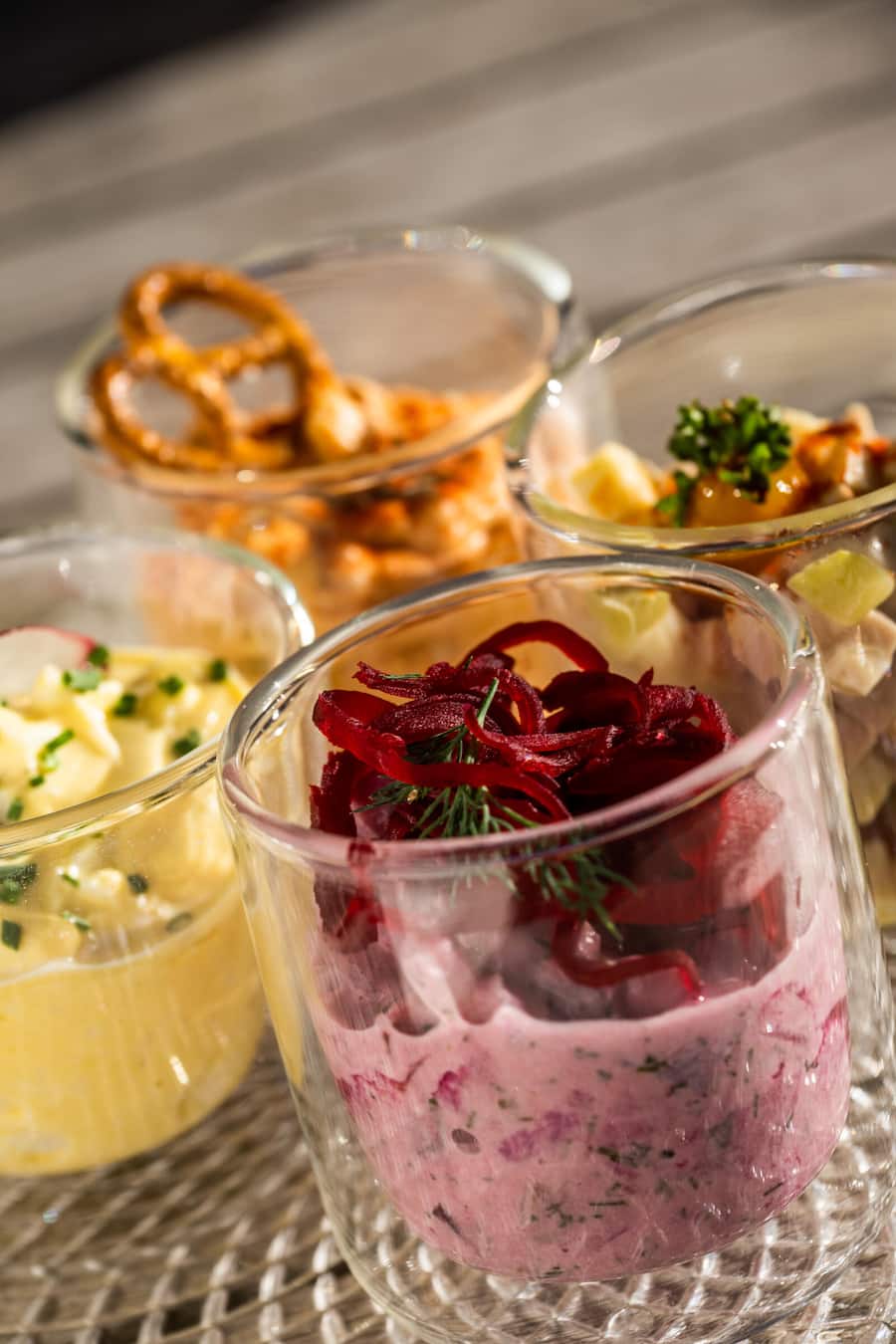 Heiko Nieder kocht Frühstück 2022: Gläschen salzig: Heringssalat mit Rande, Apfel und Dill (rotes Gläschen), Eiersalat mit Radieschen und Schnittlauch (gelbes Gläschen), Obatzter mit Paprikapulver, Kümmel ganz und Minisalzbrezel (hinteres Gläschen), Wurstkäsesalat mit Eigelbgel, Paprikapulver und Krausepetersilie.Â