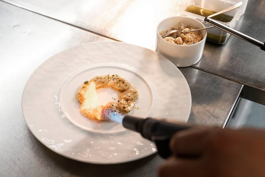 05.10.2022; Mels (SG): Roger Kalberer bereitet die Vorspeise in der Küche vor.Markbein sanft pochiert in Consommé Handgetauchte norwegische Jakobsmuschel Markbein-StreuselSchnittknoblauch. © Valeriano Di Domenico