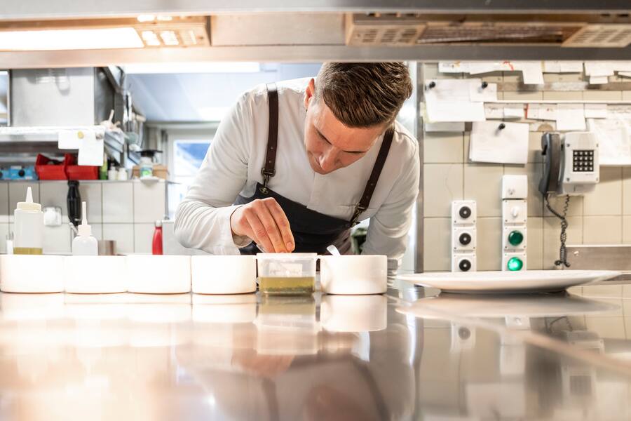 05.10.2022; Mels (SG): Roger Kalberer bereitet die Vorspeise in der Küche vor.Markbein sanft pochiert in Consommé Handgetauchte norwegische Jakobsmuschel Markbein-StreuselSchnittknoblauch. © Valeriano Di Domenico