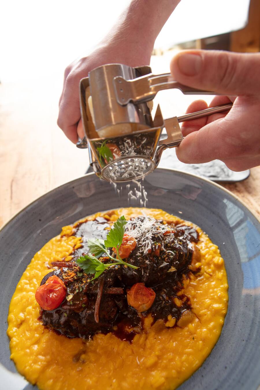 Ossobuchi in Gremolata Zart geschmorte Schweinshaxen mit rassig abgeschmecktem Safranrisotto und Steinpilzen. Dazu wird gereifter Parmesan serviert