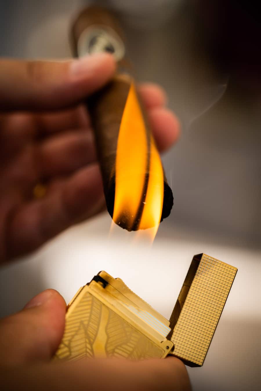 Goldenes Feuerzeug, das eine Zigarre anzündet
