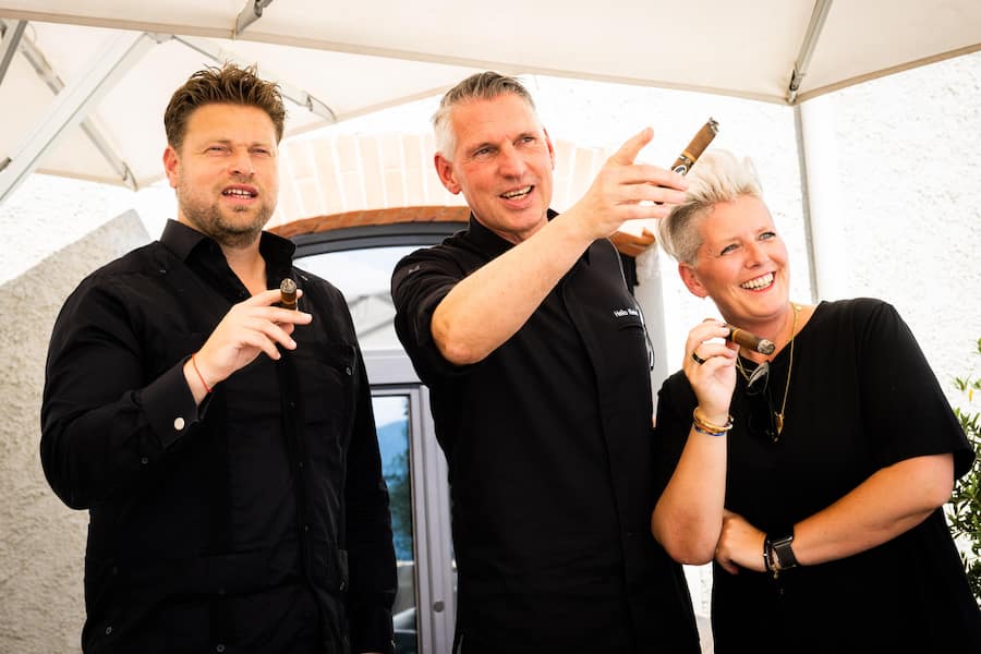 Drei schwarz gekleidete Menschen auf einer Terrasse