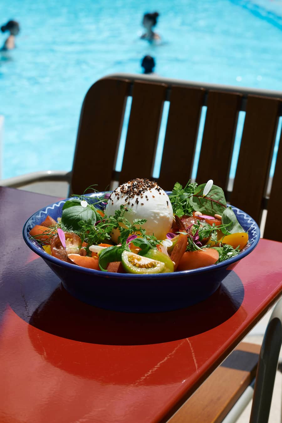 Teller mit Burrata und Cherrytomaten auf einem roten Tisch