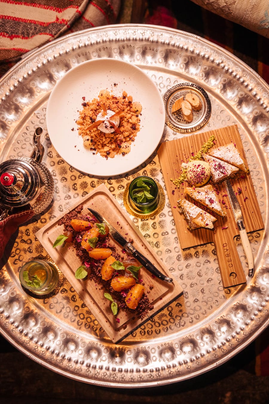 Zum Baklava gibts ein Pistache-Glace und Rosenblüten. BurtuqÄl ist ein Dessert aus Orangen, Felchlins-Schokolade, Mandelnt, Pfefferminz und Orangensirup. Und Naryla besteht aus einem Kokosnusssorbet, Kokos-Crumble, Limmeten-Gel und Ingwer. - Cervo - Zermatt Tourismus - Tapas Tour - 07/2023 - Copyright Olivia Pulver