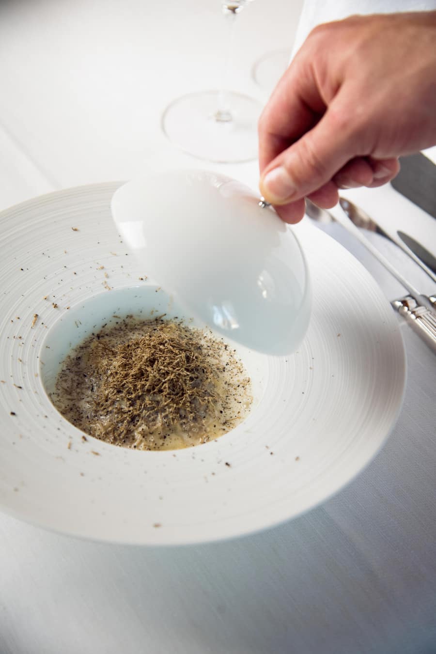 Runder weisser Teller mit einem Raviolo bedeckt von fein gehobeltem Trüffel