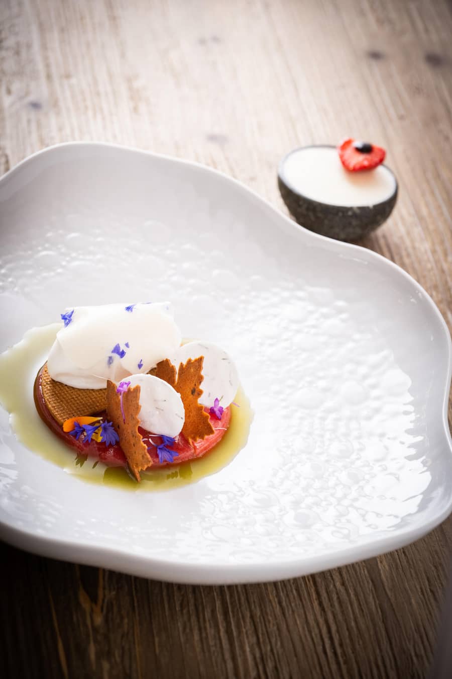 Erdbeersaftgelee, Extrakt von Rumex Sauerampfer, Schleier aus Holunder und Blütengelee, Lorbeer Mürbeteig, Tannen und Lärchenmeringue, Kardamomeis, knuspriges Erdbeerblatt, Lärchensprossen, Erdbeer Balsamico Essig mit gesüssem Rahm, wilde Süssholzwurzel