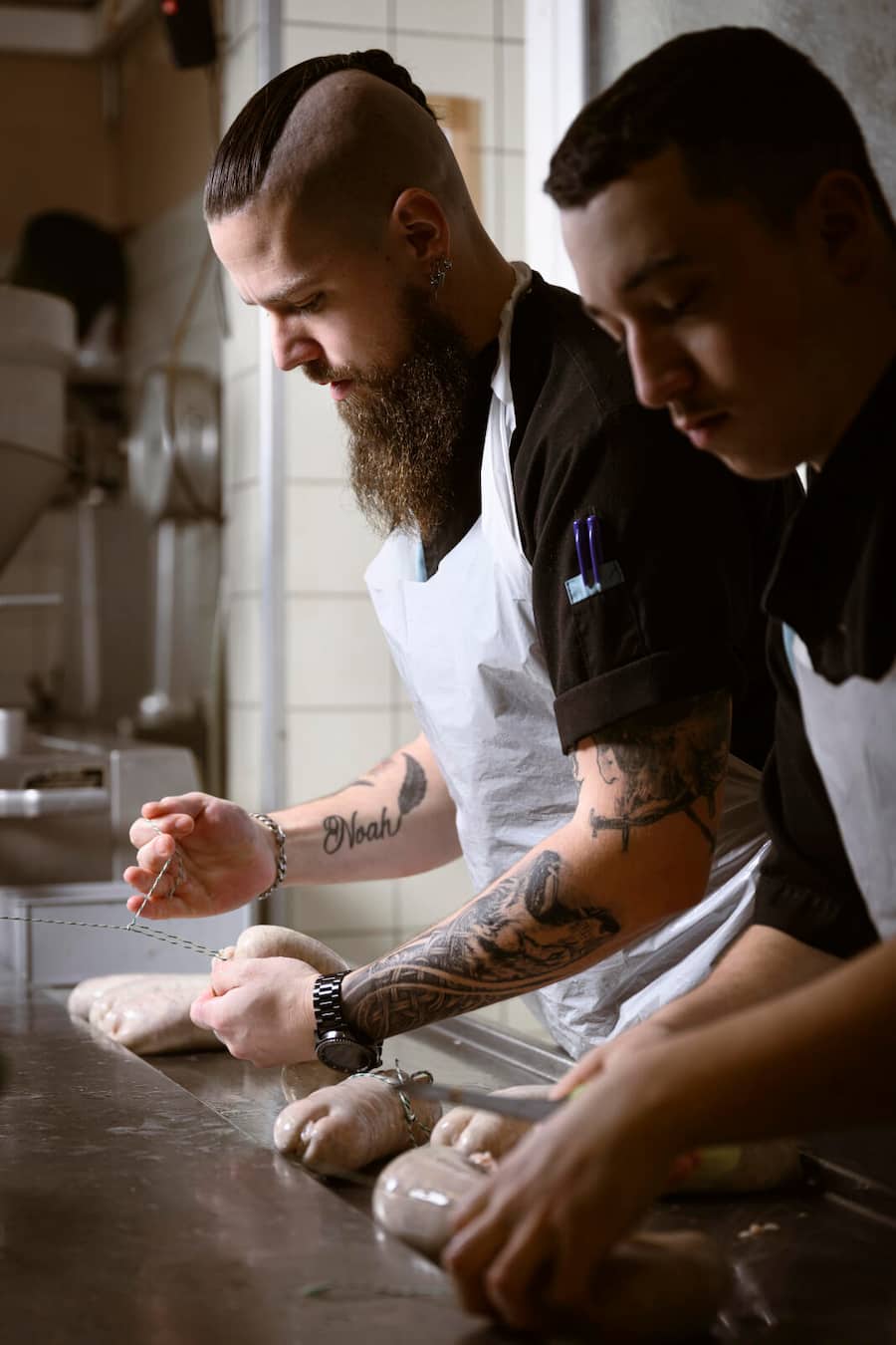 Le boucher Michaël Wyler confectionne des saucissons vaudois avec son employé dans sa boucherie, mardi 12 décembre 2023 à Lucens. (© Gabriel Monnet)