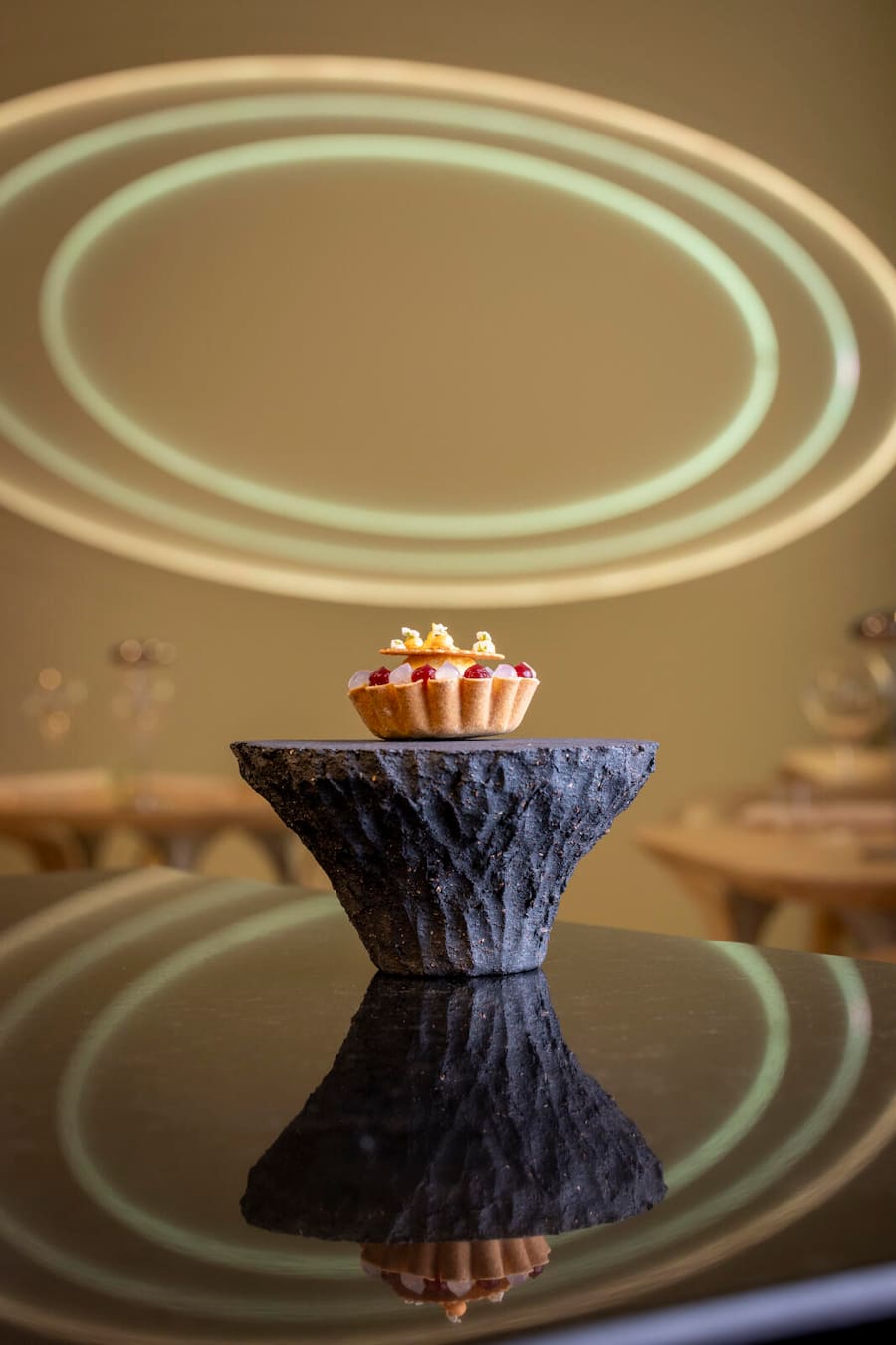 Törtchen auf dem dicken, dunklen Marmorfuss Buchweizen-Tartelette mit Sablé-Ringli zum Abheben (der 1. Biss) Mit Creme aus scharfer Salami aus Süditalien (Nduja), Süsskartoffel, gepufftes Chinoa, Ricotta-Creme mit Pollen Obendrüber Blütendekor, Peperoncino-Pulver . Restaurant CAAA, Pietro Catalano, Luzern. Aufgenommen am 30.04.2024 ©David Birri