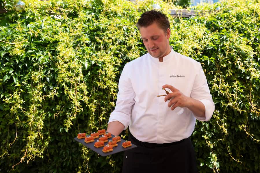 Philippe Deslarzes spraie un peu de gin sur ses tartares de truite à la coriandre et au citron.
