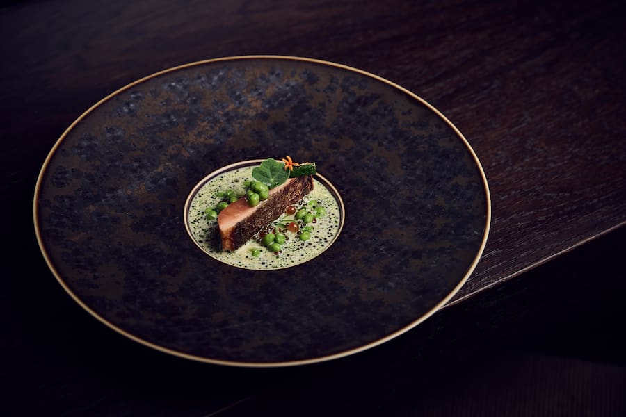 Brüggli-Saibling, auf der Haut gebratenZuchetti, grillierte Zuchetti, grillierte Erbsen, Nage auf Mirin-Basis mit Ikura (Lachsrogen), Fingerlimes, N25 Kaluga-Kaviar