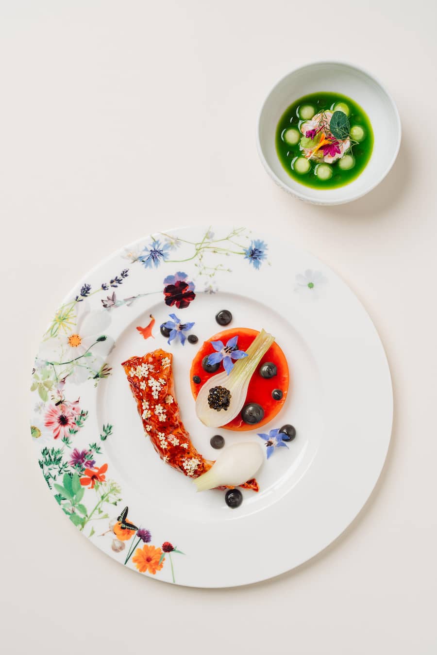 Blue lobster with senise peppers, spring onions and black garlic cream, Lobster claws with cold soup, pink pepper and cucumbers - Orsini Sommer 2024 - Mandarin Oriental Hotel Zuerich - Copyright Olivia Pulver Blauer Hummer mit Peperoni aus Senise, Frühlingszwiebeln und schwarzer Knoblauchcreme Hummerscheren mit kalter Suppe, rosa Pfeffer und Gurken Gericht: Blauer Hummer (Peperone di Senise, Frühlingszwiebeln, schwarzer Knoblauchcreme)