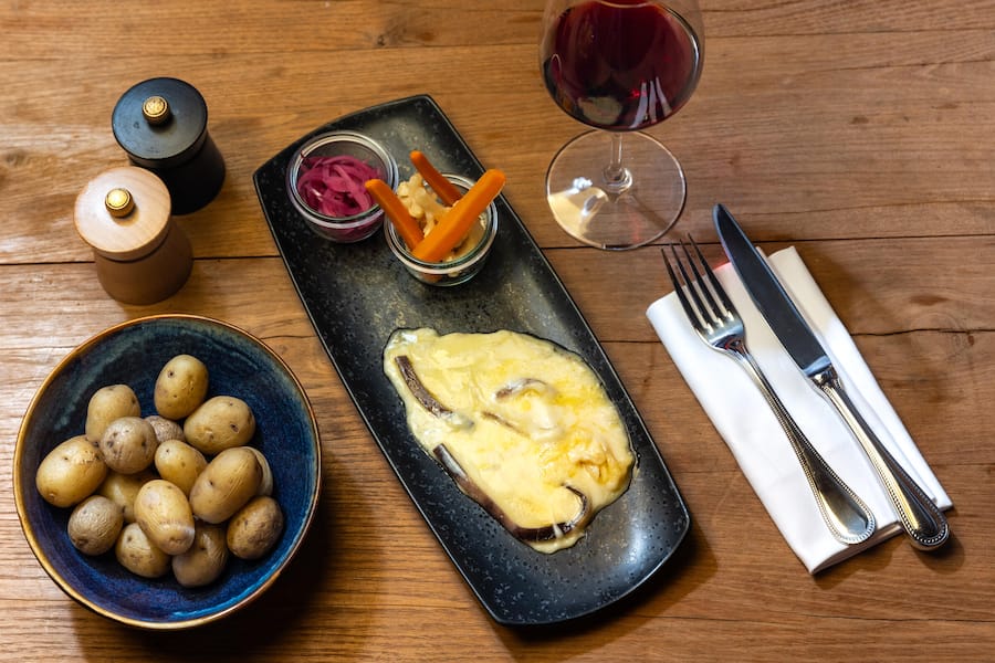 Raclette im Seehus Fotografiert am 20.11.2024 im Restaurant Seehaus in Herrliberg. Gericht: Henry Rouge Käse mit 1 dl Henry Rouge Gamaret-Garanoir, Kartoffeln, eingelegte Balsamico Zwiebeln