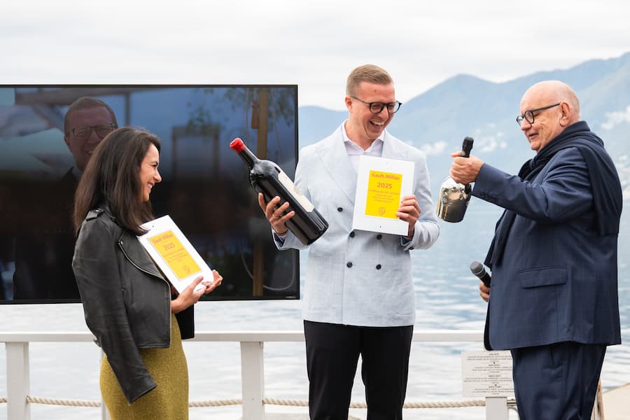 Fabian Mennel, Mitte, Sommelier des Jahres, und Ines Triebenbacher, links, Gastgeberin des Jahres freuen sich am Montag, 30. September 2024, ueber ihre Auszeichnungen uebergeben von Gault Millau Chefredaktor Urs Heller, vor dem Hotel Eden Roc in Ascona. Der Tessiner Chefkoch im hoteleigenen Restaurant ''La Brezza'' wurde zum Koch des Jahres 2025 durch den Gastronomiefuehrer Gault-Millau gewaehlt. (KEYSTONE/Ti-Press/Samuel Golay)