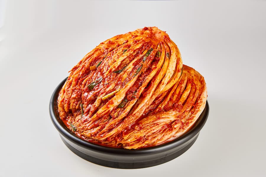 Cabbage kimchi is placed in a ceramic bowl.