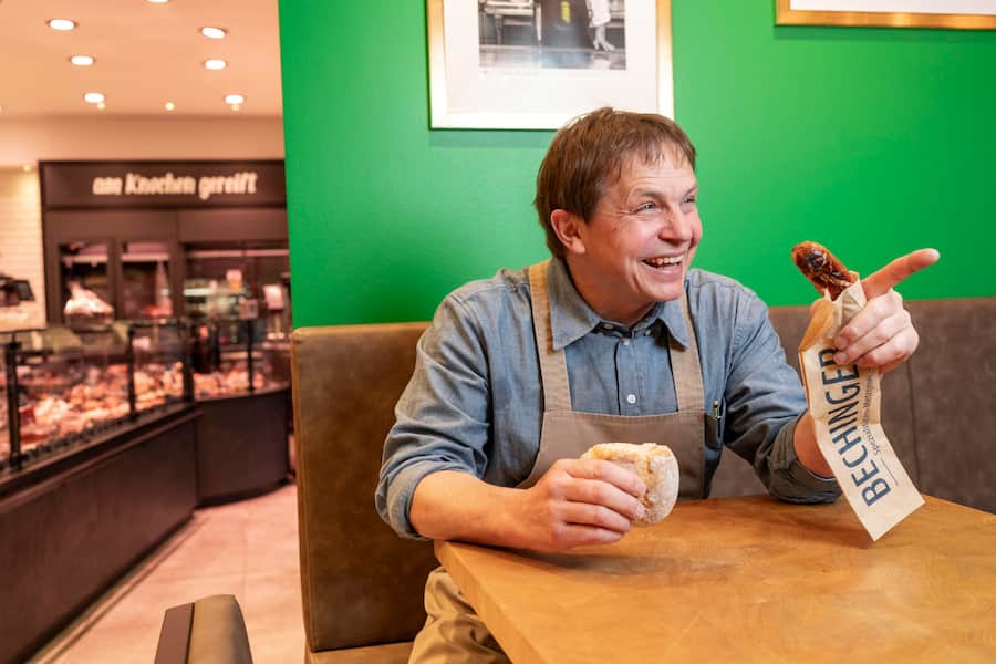 Bechinger Bratwuerste, St. Gallen-St Georgen, Jörg Bechinger geniesst seine frisch gemachte Olmabratwurst mit einem Bürli in seinem Shop-Café