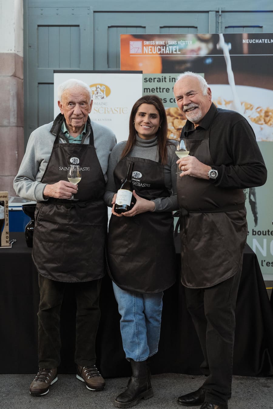 Elodie mit Grossvater Jean-Claude (links) und Vater Jean-Pierre (rechts) am Non Filtré Event in La-Chaux-Fonds - Bio-Winzerin Elodie Kuntzer produziert Non Filtré - Domaine Saint-Sébaste - Kuntzer SA - Januar 2025- Copyright Olivia Pulver