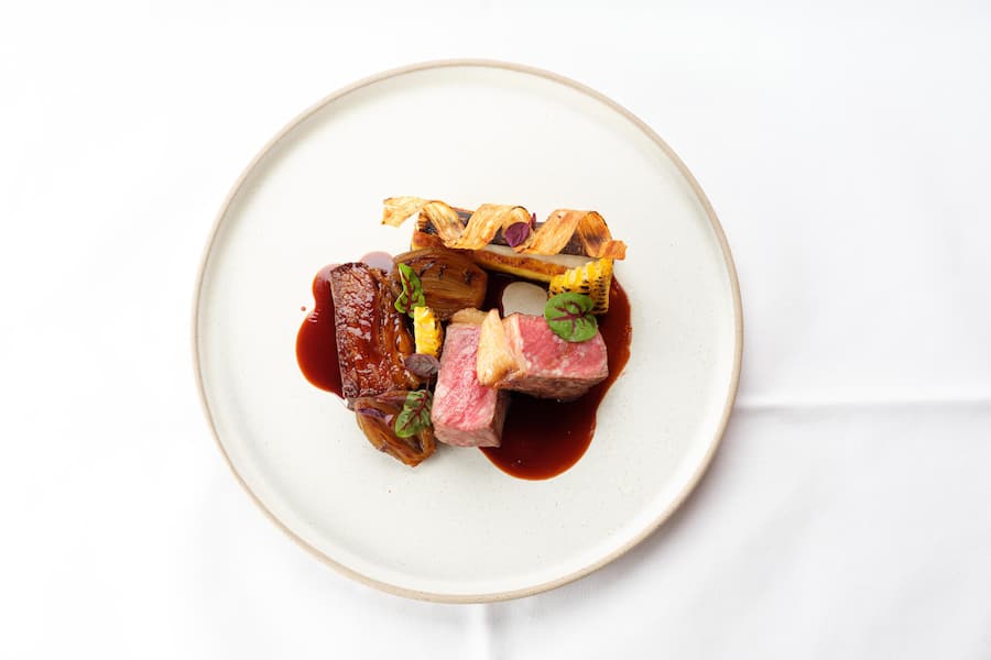 Menü Hauptgang Gourmet Menü Swiss Black Angus Rindsentrecote Swiss Black Angus Rindsentrecote geschmortes Short Rib Schweizer Polenta geflämmter Zuckermais Schwarzwurzel Variation (Püree, Chips, kontiert) Kalbsjus mit Tasmanischem Bergpfeffer karamellisierte Schalotte Amaranth Blätter Veine Sprossen