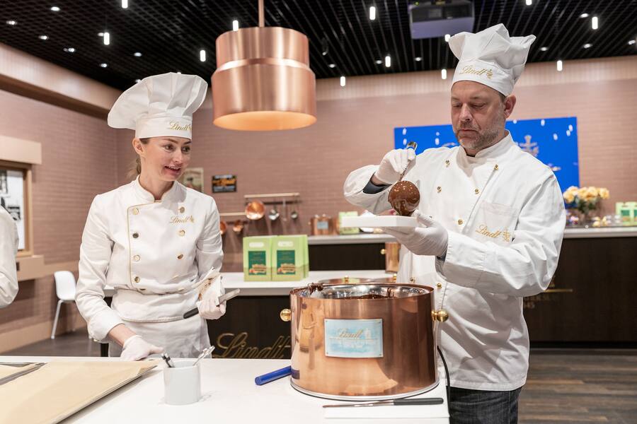 Kateryna von den «Maîtres Chocolatiers» schaut GaultMillau-Autor Alex Kühn beim Schokoladegiessen über die Schulter.