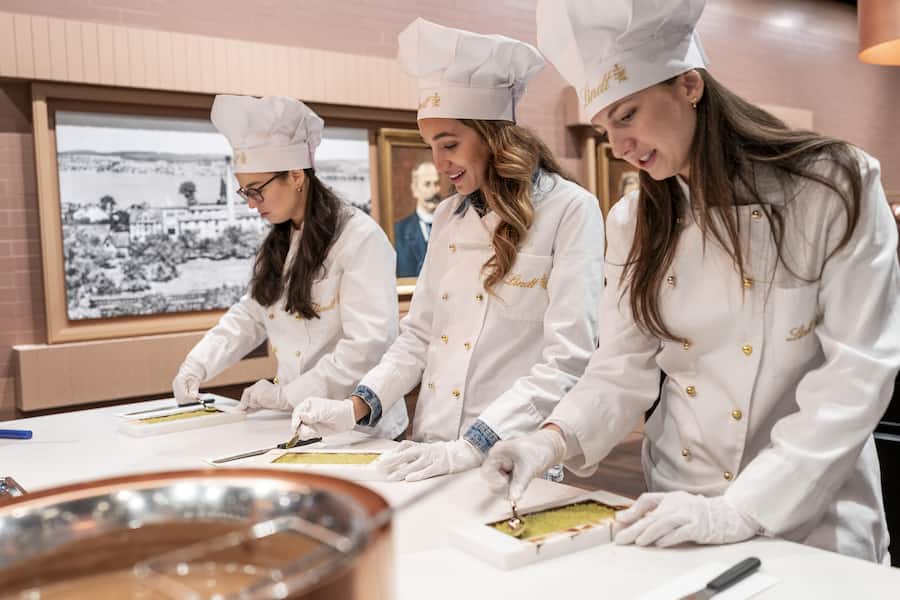 Volle Konzentration für höchsten Schoggi-Genuss: Drei Kursteilnehmerinnen beim Verstreichen der Füllung.