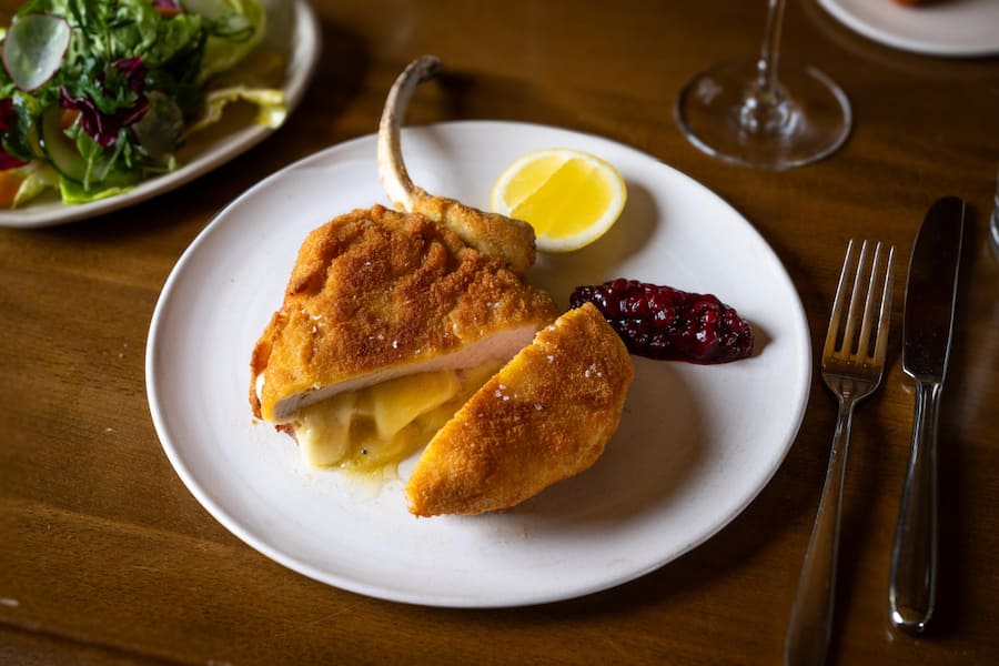 Tomahawk Cordon Bleu mit Rösti Sticks Appenzellerkäse, geräucherter Schinken, Trüffel-Rösti Fritten, Sommer Wildkräutersalat und Preiselbeer Chutney