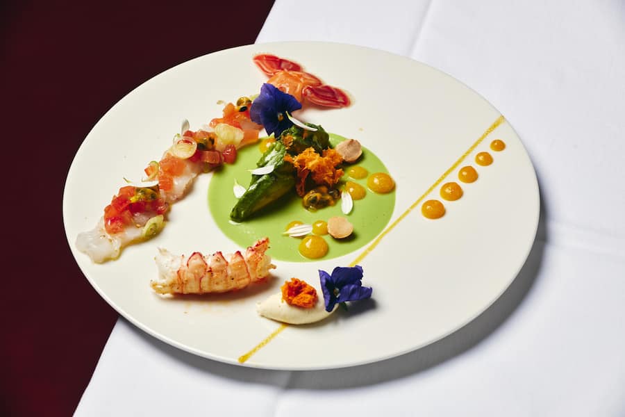 Duett von marinierten und gebratenen Langoustinen mit Passionsfruchtvinaigrette, Avocado-Creme, gerösteten Macadamianüssen und Blüten