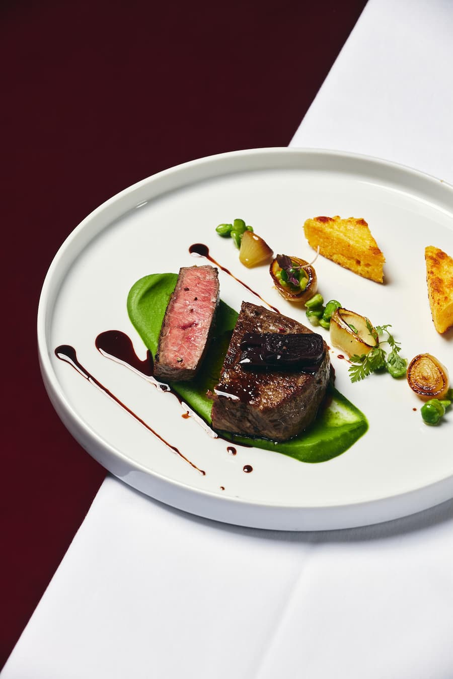 Rinderfiletmedaillon mit Rotwein-Schalottenjus auf Erbsen, karamellisierten Zwiebeln und Polentaschnitten
