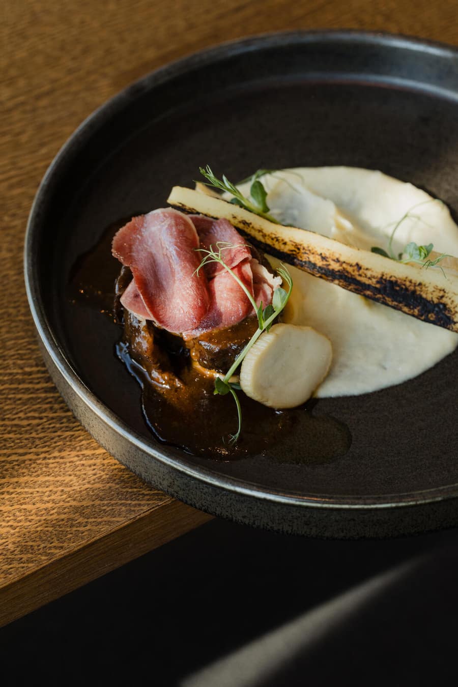 Rindshaxe vom Wagyu geschmort, Rindszungen Carpacchio, Pastinaken Püree, Glasierte Pastinaken, Sautierte Kräuter Seitlinge, Fritierte Petersilie, Portrait Uma Tower Restaurant, 03. März 2025, Uma Tower Restaurant in Bern, Copyright Roy Matter Uma Tower, Ostermundigen, BE, 03/2025