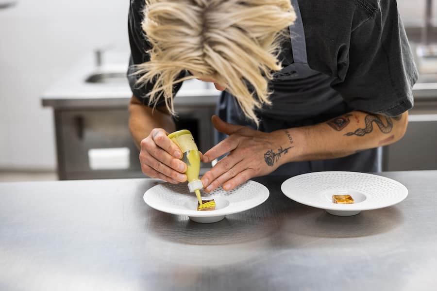 13.06.2025, Vals GR, Restaurant Silver, Papada vom Iberico Schwein, Kohlsauce mit Kimchi-Saft und Liebstöckelöl; Austern mariniert mit Schalotten und Champagneressig(photo by Remy Steiner for Gault Millau)
