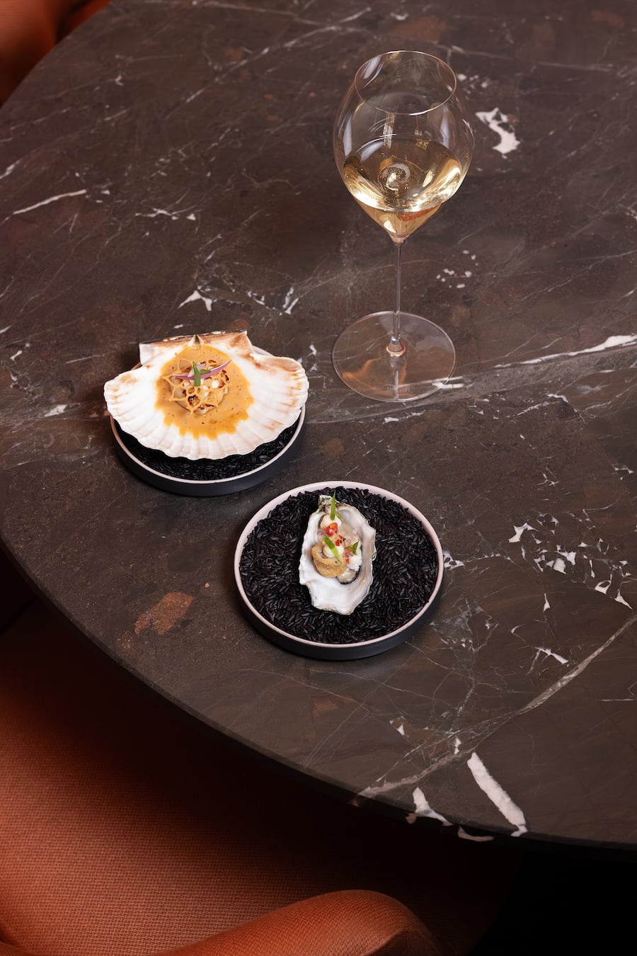 Ein Gericht von Koch Bernd Fabian aus roher Jakobsmuschel mit Schnittlauch und einer Vinaigrette und gebackene und rohe Auster mit Paprika & Stangensellerie in einer Schabermuschel, Champagner Laurent-Perrier Héritage dazu, 13. August 2025, Hotel Chasa Montana Samnaun, Copyright: Simone Lombard