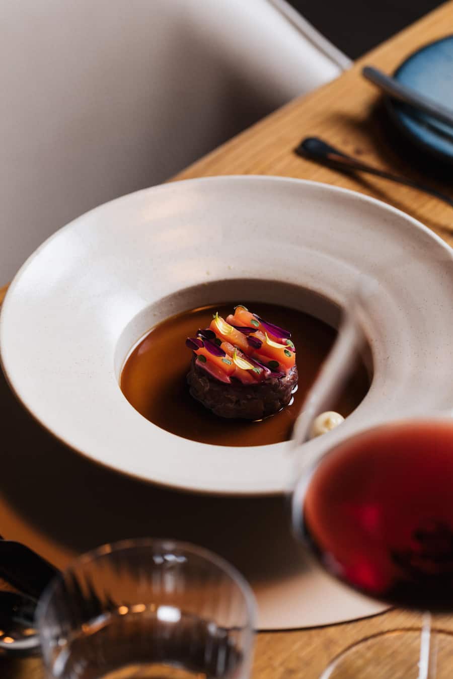 Bison-Tatar, gebeizt mit Koji, Mayo mit geräuchertem Aal, Wachtelconsommé mit Szechuanpfeffer und Poulet-Fett-Brioche, Aux Trois Amis X Krebs&Steiner, 13. Oktober 2025, Restaurant Aux Trois Amis, Schernelz, Copyright Roy Matter