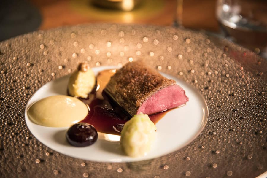 Rehrücken mit Walnuss-Pfefferkruste, dazu Blaubeergel, Polenta, Sherryessig-Hollandaise und Rosmarinjus.