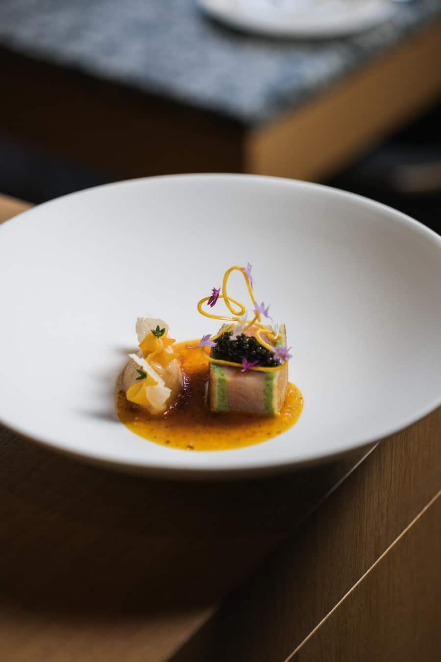 Zwischen den dünnen Teigschichten stecken Thymianfarce und gebeizter Saibling, in der säuerlichen Sauce Quitten und Safran. Küchenchef André Kneubühler THE OMNIA. 17. Oktober 2025, THE OMNIA, Auf dem Fels, 3920 Zermatt, Copyright Roy Matter Titelstory GM-Magazin 4/25 André Kneubühler The Omnia Zermatt
