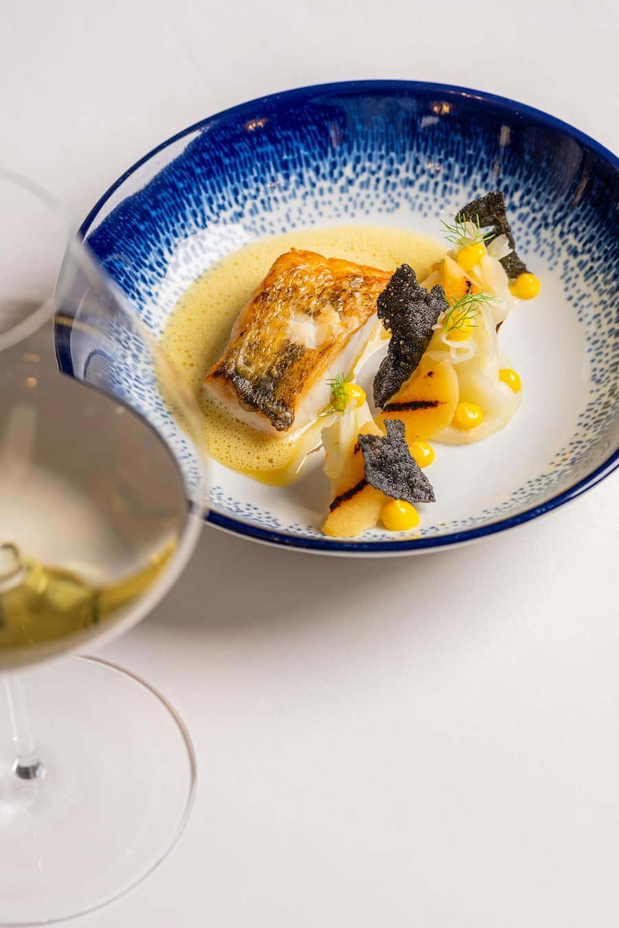 Gebratener Zander aus dem Bodensee mit mariniertem Fenchel, grillierter Quitte und Safran-Buttersauce, dazu ein Chardonnay von Thomas Studach fotografiert im Restaurant Schluessel Mels am 28. Januar 2026 fuer die GaultMillau Serie Winzer X Starchef. Bild Yanik Buerkli
