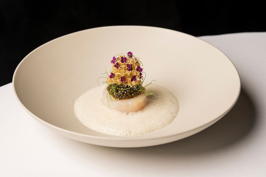 Four-Hands-Dinner mit Marcel Koolen und Rolf Fliegauf im Restaurant 7132 Silver in Vals. Gericht von Rolf Fliegauf: Konfierter Kabeljau, Fingerlimes, Kaviar, Kombualgen, Kartoffel-Rauchaalkompott, Dashi Beurre Blanc. Fotografiert am 20. Maerz 2026 fuer GaultMillau. Bild Yanik Buerkli