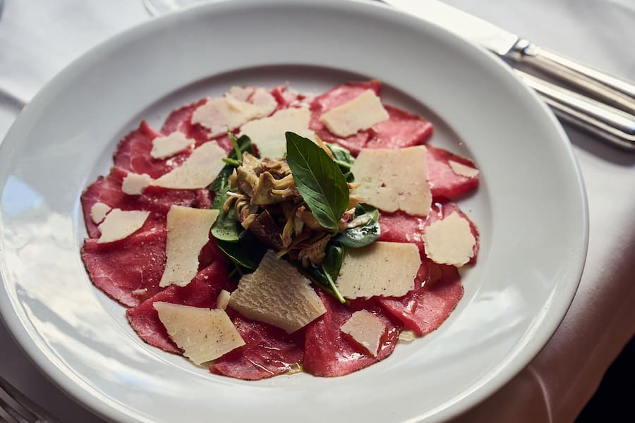 Rindscarpaccio mit Olivenöl, frischer jungspinat, Pecorino-Splitter