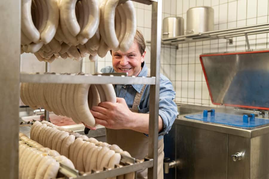 Bechinger Bratwuerste, St. Gallen-St Georgen, Jörg Bechinger schneidet die Olmabratwurstschlange mit dem Messer in einzelne Würste