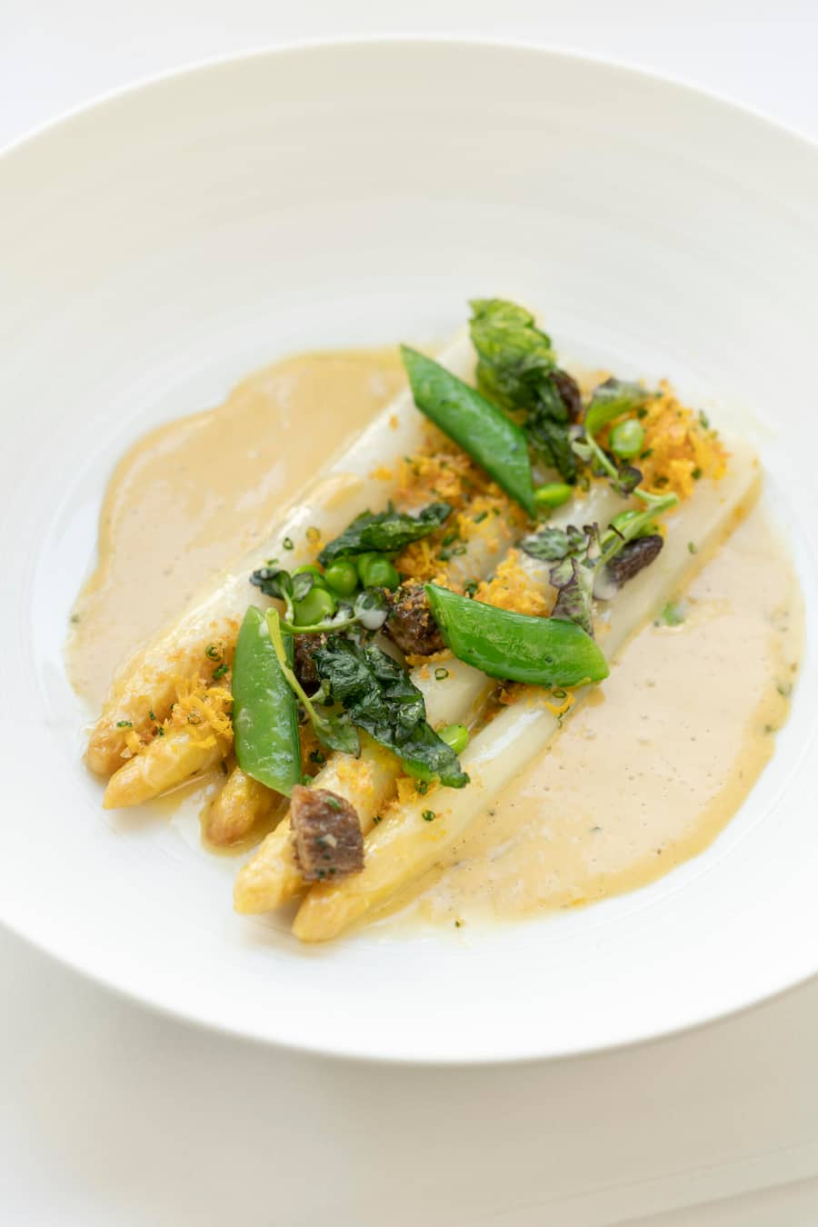 Badischer Spargel Creme aus geräuchertem Sauerrahm und Bärlauch. Mit Erbsen, Morcheln und Zuckerschoten.