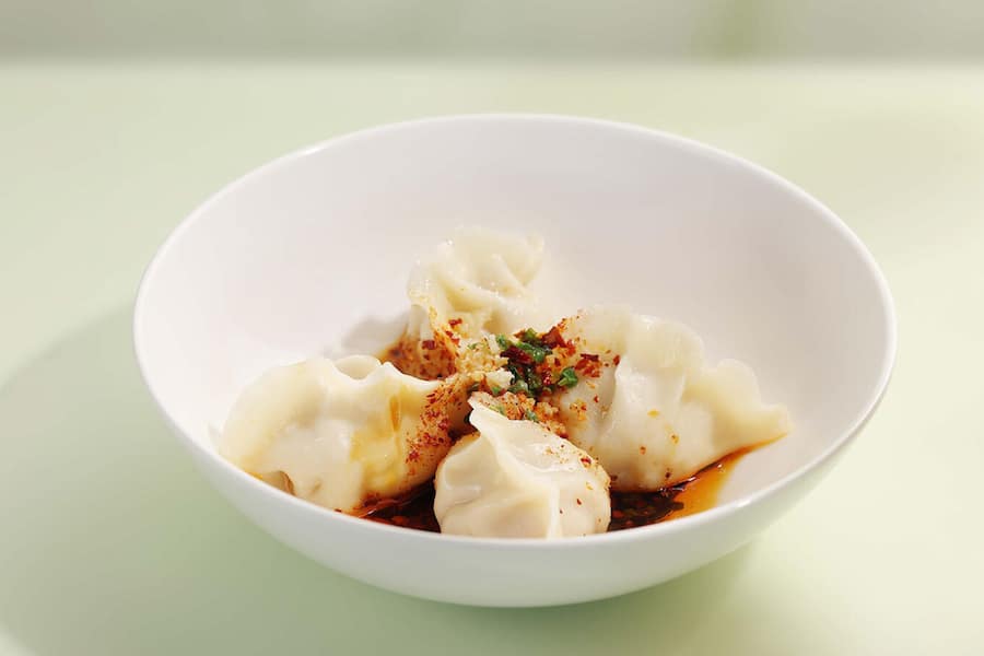Handgemachte Dumplings mit Abalone-Füllung, garniert mit Chiliöl.